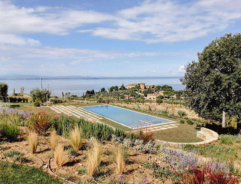 Foto panoramica di una piscina circondata dal verde, con vista sul lago.